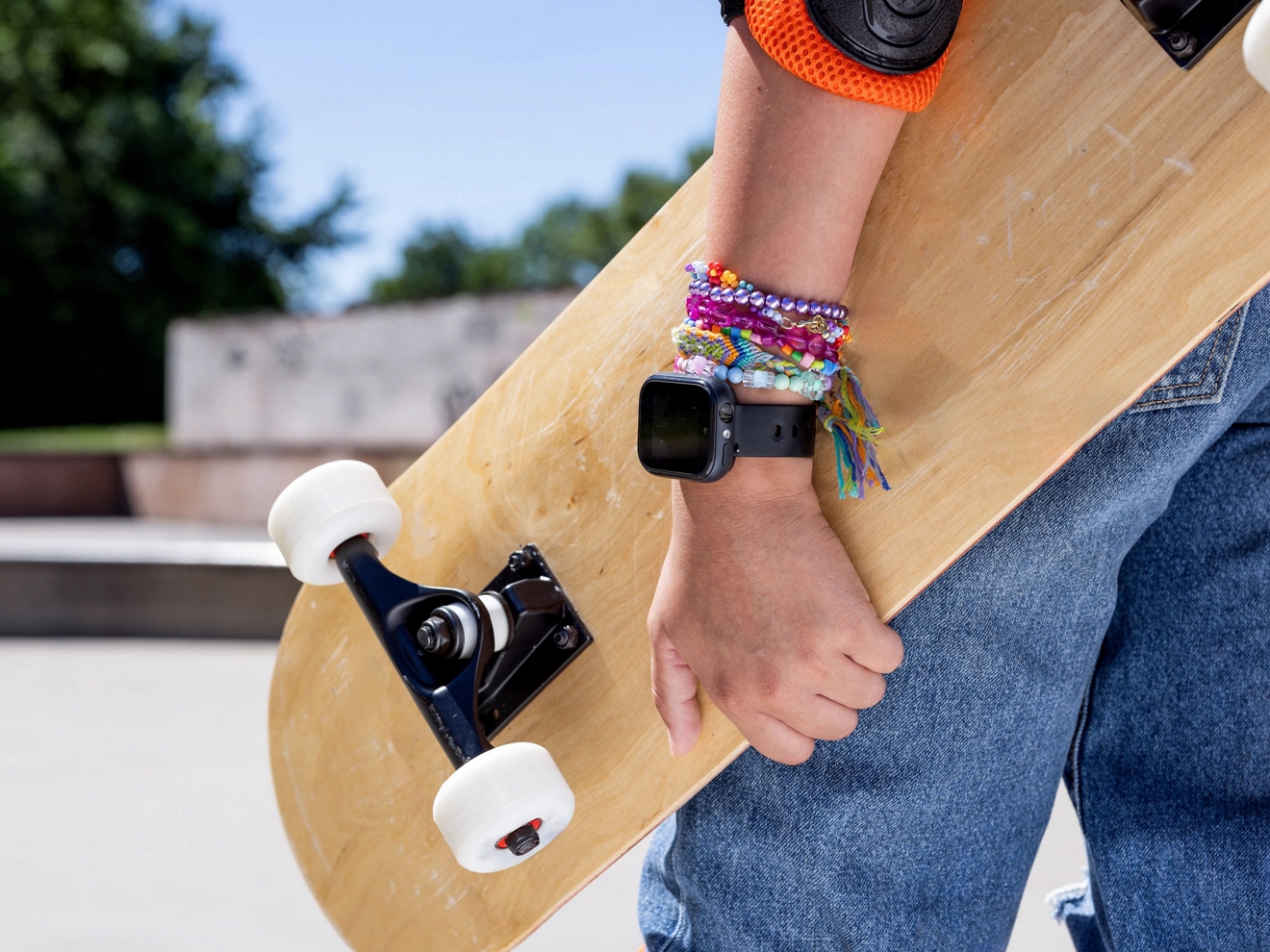 SyncUP KIDS Watch on an arm holding a skateboard.